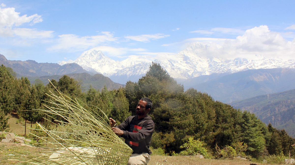 म्याग्दीको रुइसेमा डोको बुन्दै स्थानीय, पृष्ठभूमिमा अन्नपूर्ण हिमाल 